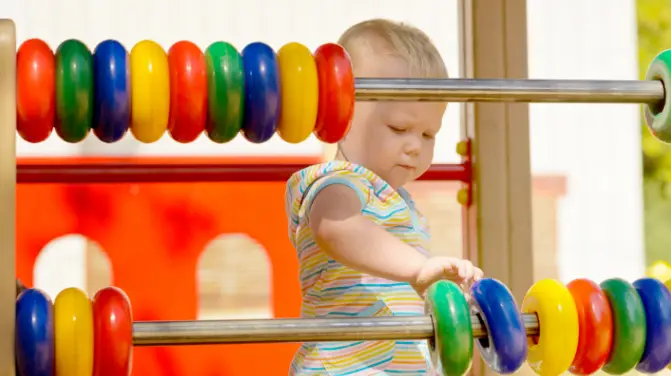 Child playing on a large colourful abacus at the playground