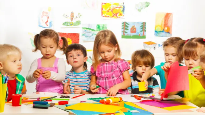 Children at a drawing table, playing and drawing with crayons and enjoying various games